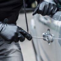Auto theft: Car thief trying to break into a car with a screwdriver.